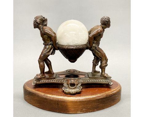 A 19th/early 20thC bronze of two men carrying a basket containing a polished quartz ball, mounted on an oak base, W. 29cm H. 