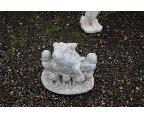 A cast concrete garden statue in the form of pigs over a gate 