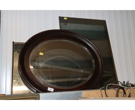 An oval framed bevel edged wall mirror together with two others