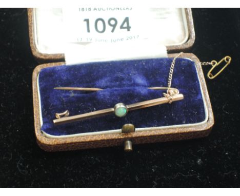 A yellow metal bar brooch stamped 9ct having a central opal