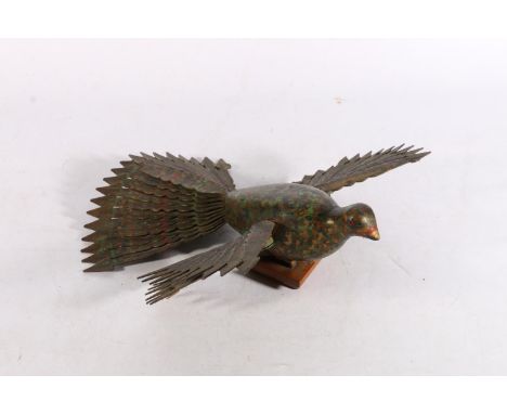 Folk art carved wood sculptural model of a peacock with articulated wings and tail feathers raised on plinth base, 33cm long.