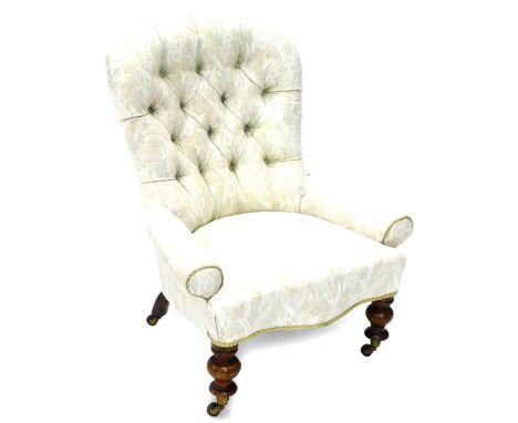 A Victorian mahogany low chair, reupholstered in cream floral fabric with piped borders, on turned legs with ceramic castors.