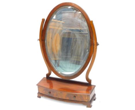A mahogany dressing table mirror, the oval plate with a bevel edge on shaped supports with a bow fronted base, inset with two