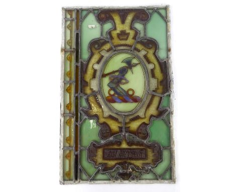 A 19thC stained glass panel, decorated with a crest of an armoured arm with bent elbow and an axe, and motto below Aut Inveni