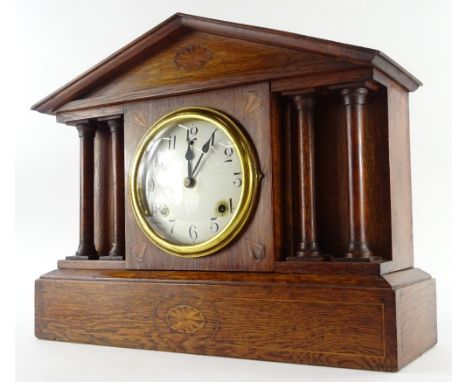 An early 20thC oak and marquetry portico shaped mantle clock, the enamel type dial with Arabic numerals and a brass bezel fla