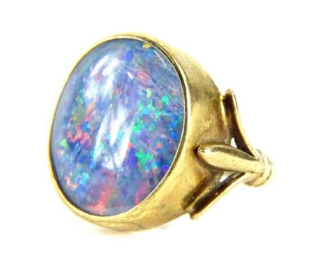 A 9ct gold opal dress ring, with opal doublet, in a rub over gold setting, with three splayed shoulders, on a cut band, 5.2g 