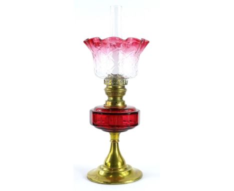 A late 19th/early 20thC oil lamp, with a part cranberry tinted shade, a ruby tinted reservoir and a tapering brass base, 50cm
