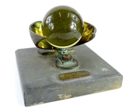 A late 19th/early 20thC Campbell Stokes sunshine recorder, with glass ball and bronzed metal mounts on a black slate base, la