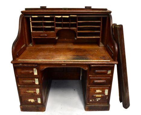 An early 20th century oak roll top twin pedestal desk, the tambour front enclosing pigeonholes, raised on two pedestals, each
