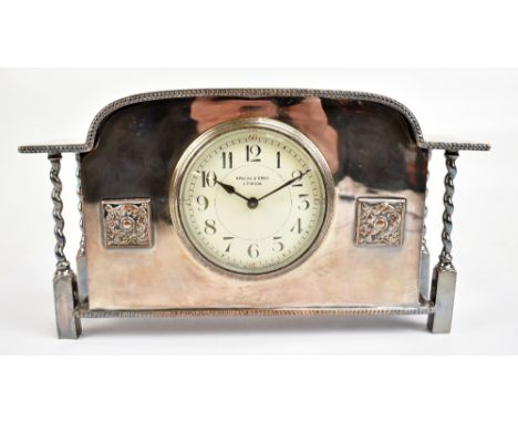 ALBERT EDWARD JONES; an Arts and Crafts silver plated mantel clock with applied square cartouches each with floral detail sur