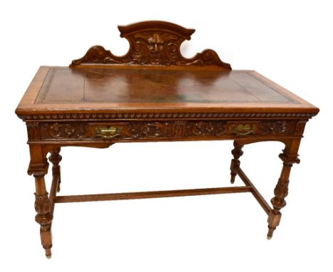 A late Victorian carved oak writing table, the carved gallery back with central mask head panel and tooled brown leather inse