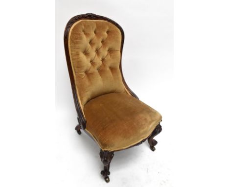 A mid-Victorian solid rosewood nursing chair with button upholstered back, scrolling decoration to the arms and knee carved s