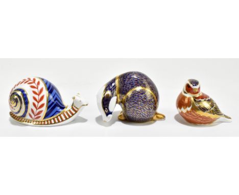 ROYAL CROWN DERBY; three paperweights comprising Badger, Snail (lacking stoppers) and a bird (with gold stopper), all with pr