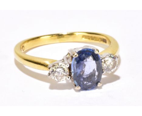 An 18ct yellow gold three stone ring, with central oval pale blue stone flanked by twin round brilliant cut diamonds totallin