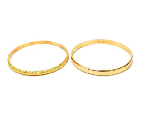 Two 18ct yellow gold bangles, the first with textured design, the second of plain design, the textured bangle external diamet