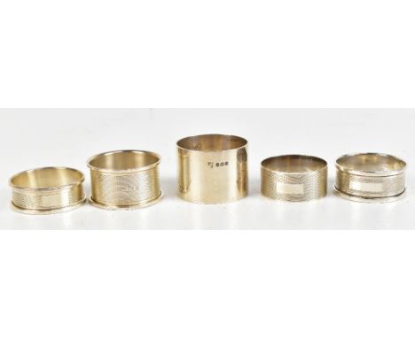 Five hallmarked silver napkin rings, four examples with engine turned decoration, to include an example by Henry Griffin &amp