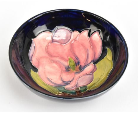 MOORCROFT; a small 'Magnolia' pattern footed bowl on navy ground, impressed marks to base,&nbsp;diameter 11.3cm.Additional In