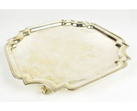 MAPPIN &amp; WEBB; a George V hallmarked silver salver of square form, with cast scalloped edge, raised on four scrolling fee