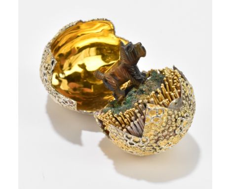 STUART DEVLIN; an Elizabeth II hallmarked silver gilt surprise egg, the hinged cover enclosing a replacement terrier dog, Lon