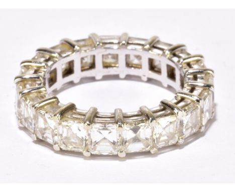 A white metal full hoop eternity ring set with nineteen square step cut diamonds totalling 5.50ct, size L, approx 5.5g. Footn