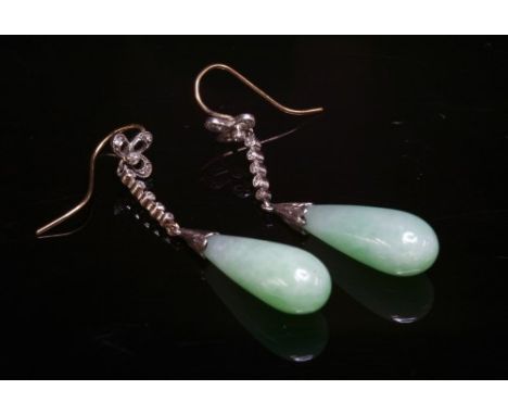 A pair of Art Deco jade and diamond drop earrings, with a jade pippin set to an engraved cap. The pippin suspended below a ba