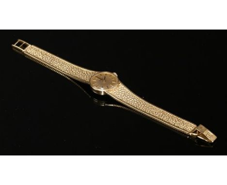 A ladies' 9ct gold Omega mechanical bracelet watch, with a circular champagne dial, with raised gilt and black batons and bla