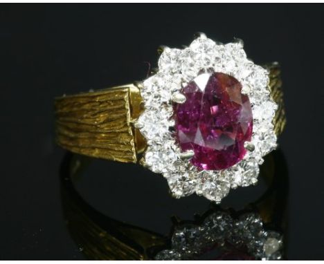 An 18ct gold, ruby and diamond cluster ring, c.1975, an oval mixed cut ruby, surrounded by brilliant cut diamonds, all claw s