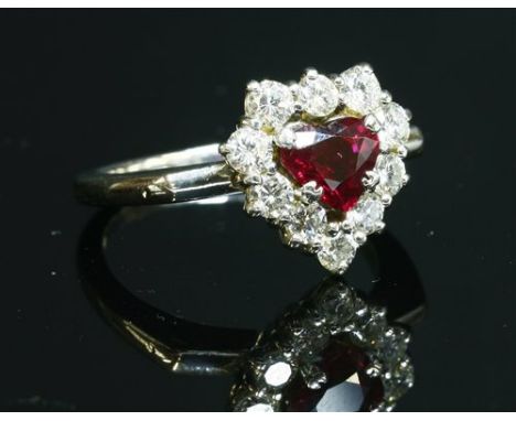 An 18ct white gold, ruby and diamond cluster ring, with a heart cut ruby, four claw set to the centre. A border of brilliant 