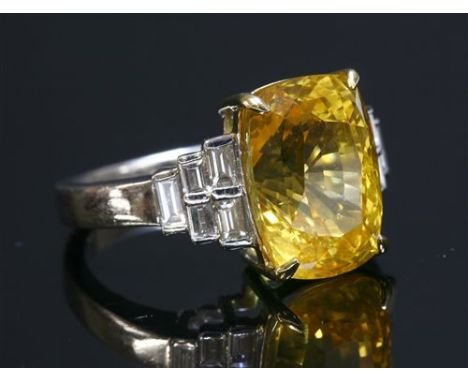 An 18ct white gold single stone yellow sapphire ring, with diamond set shoulders, with a cushion cut yellow sapphire, four cl