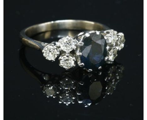 A white gold, sapphire and diamond ring, with an oval mixed cut sapphire, claw set to the centre in a rex collet. A trefoil o