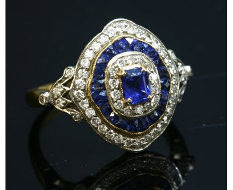 A two colour gold, sapphire and diamond target-style cluster ring, with an emerald cut sapphire, four claw set in yellow to t