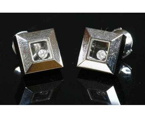 A pair of 18ct white gold 'Happy' diamond earrings by Chopard, with a brilliant cut diamond, rub set to a plain collet to gla