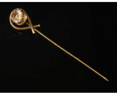 An early 20th century gold stick pin, with a circular mixed cut topaz, claw set to a looped wire head. Tested as approximatel