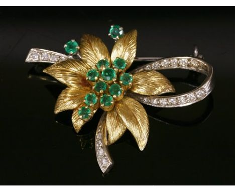 An 18ct two colour gold, emerald and diamond brooch, c.1970, by Cropp and Farr. A flower head cluster with a dispersed cluste