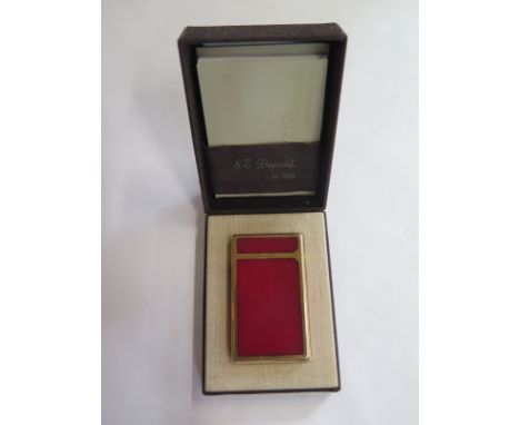 A retro S.T. Dupont Paris lighter with gold plated and red lacquered case, indistinct engraved initials to small panel, with 