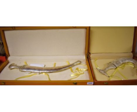 A 20th century Omani Janbiya/ Khanjar, with a silver coloured sheet metal covered handle with pierced and a curved sheath wit