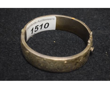 A silver bangle, engraved with flowers
