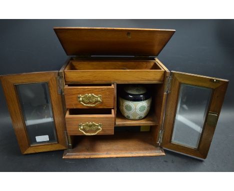 An Edwardian oak two door smokers cabinet, glazed doors, fitted interior, with Meerschaum pipe and mixing bowl