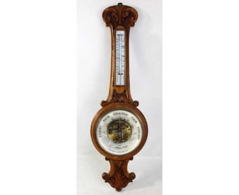An Edwardian carved oak aneroid wheel barometer with thermometer above barometer dial inscribed 'Pearce &amp; Sons, Leeds &am