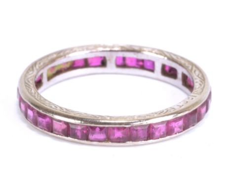 An early 20th century 18ct white gold and ruby full eternity ring with square cut stones and engraved decoration to the sides
