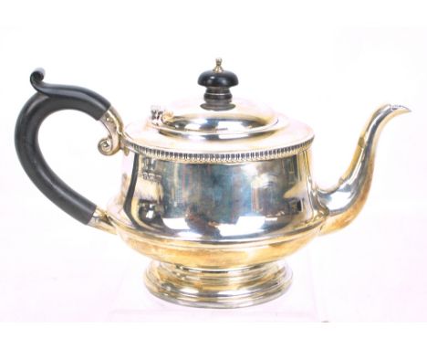 A George V hallmarked silver teapot of circular form, with C-scroll handle, gadrooned decoration and stepped circular base, m