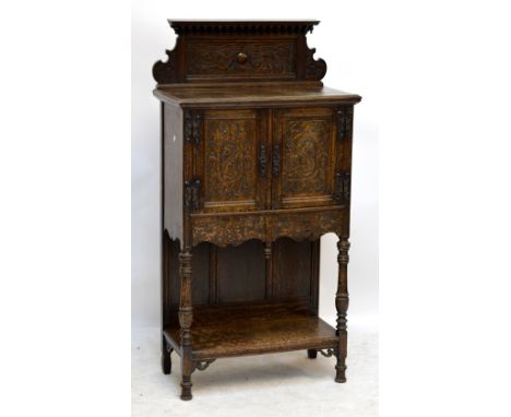 An Edwardian carved oak side cabinet with raised back above two panel doors, shelf beneath and baluster ring turned and block