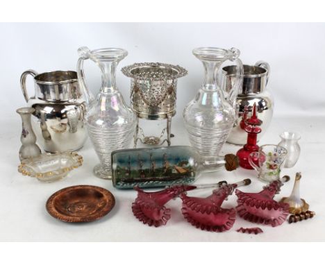 An electroplated bottle coaster with pierced decoration, raised on four stretchered legs, 22cm, and a pair of jugs, crested a