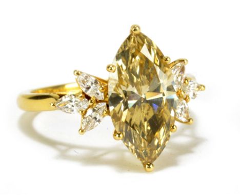 An impressive yellow metal fancy diamond ring, the principal champagne tinted marquise cut stone weighing approx 3.3cts, with