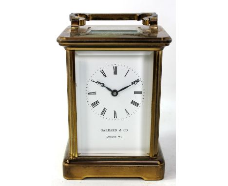 A brass cased carriage clock with swing carry handle, the white enamel dial set with Roman numerals inscribed 'Garrard &amp; 