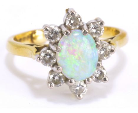 An 18ct yellow gold and opal cluster ring, the oval cabochon weighing approx 1.5ct within border of eight round cut diamonds,