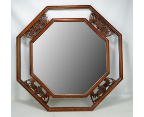 A Chinese hardwood octagonal mirror with four carved bats, diameter approx 78.5cm.