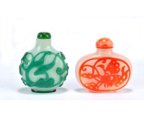 Two Chinese Peking glass style carved snuff bottles, one in green decorated with fish, the other in red/orange with a butterf