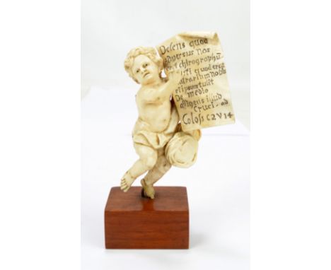 A 19th century carved ivory figure of a cherub holding aloft the Epistle of Paul to the Colossians 2:14, raised on rectangula