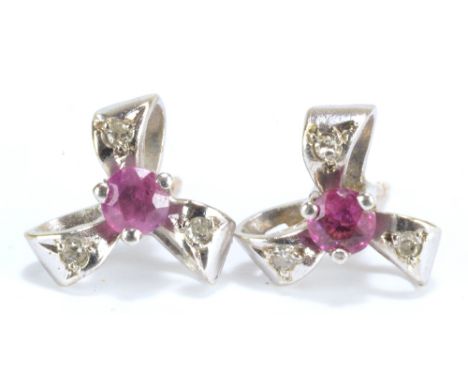 A pair of 9ct white gold ruby ear studs set with round cut pale pink stone in claw setting and three bow shaped mounts, each 